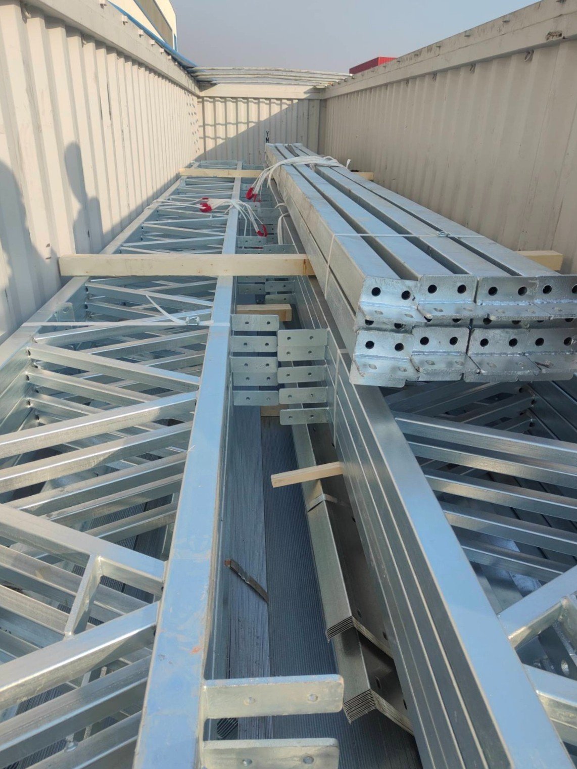 Galvanised steel trusses and punched steel sections loaded in a shipping container